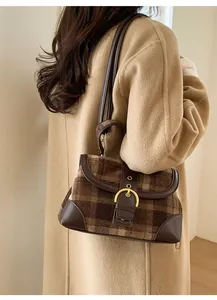 Detail of vintage brown plaid handbag with retro metal buckle and leather trim
