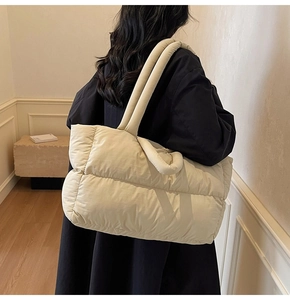 Sac cabas matelassé blanc crème en duvet porté à l'épaule dans un intérieur moderne
