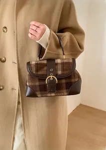 Detailed view of vintage brown plaid underarm bag with gold buckle and leather trim