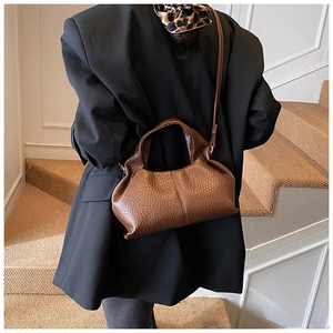 Détail du sac nuage en cuir marron à motif litchi avec plis souples et bandoulière fine
