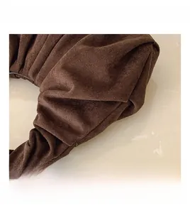 Detailed close-up of dark brown pleated suede texture on a minimalist headband