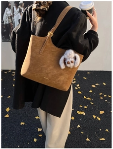 Close-up of retro brown suede tote bag with gold logo and fluffy white doll pendant