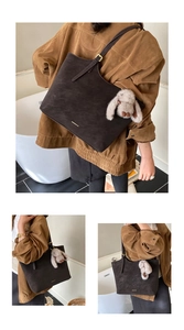 Detail of dark brown matte tote bag featuring golden hardware and plush rabbit charm