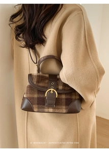Detail of retro plaid handbag with brown leather trim and golden metal buckle closure