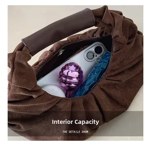Detail showing internal capacity of the brown pleated suede bag with everyday essentials