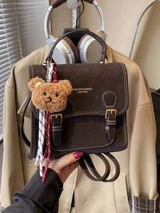 Retro brown leather backpack with white stitching, gold hardware and plush bear charm