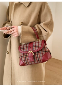 Detail of plaid wool and red leather shoulder bag with gold buckle on a camel coat
