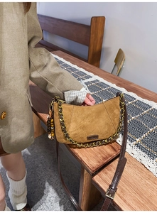 Detail of brown suede hobo bag featuring gold chain handle and decorative wooden beads