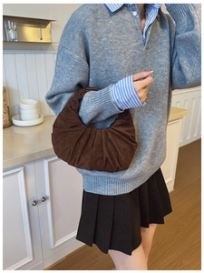 Detail of a brown pleated suede crescent bag showing premium matte texture and structure