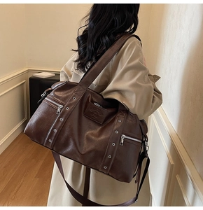 Détail du sac fourre-tout en cuir marron avec fermetures éclair et bandoulière large