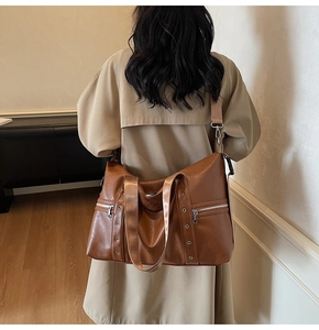 Détail du grand sac cabas en cuir marron avec zips latéraux et œillets argentés
