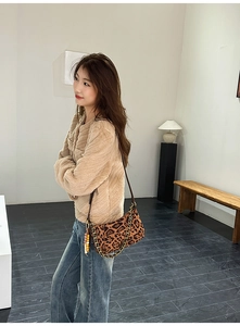Detailed close-up of leopard print suede shoulder bag with gold chain and charm