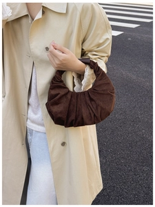 Detail of dark brown pleated crescent handbag showing fine suede texture and soft draping