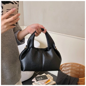Détail du sac à main noir plissé montrant la texture craquelée brillante et les anses