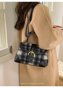 Detail of retro black and white plaid wool handbag with golden buckle on beige coat