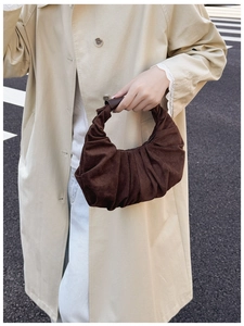 Detailed view of dark brown suede handbag featuring elegant pleats and leather handle