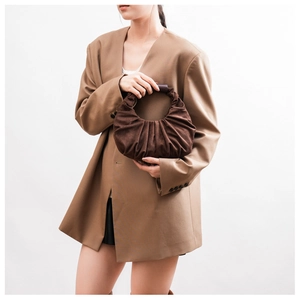 Detail of deep brown suede crescent bag featuring distinctive pleated texture and sleek curved handle