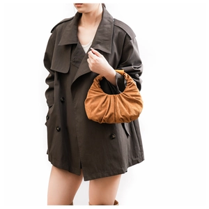 Close-up of brown suede pleated handbag styled with a classic oversized trench coat