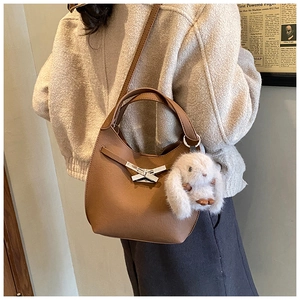 Brown leather bucket bag with silver cross buckle and white plush rabbit charm detail