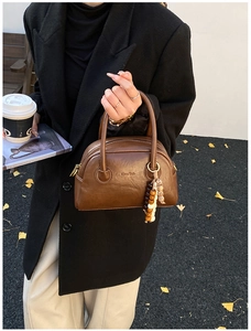 Close-up of vintage brown leather bowling bag with Chre'bab logo in an autumn street setting
