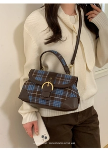 Model wearing retro plaid saddle bag with leather trim and gold buckle closure detail