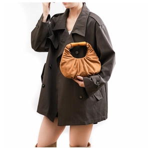 Detail of a brown suede pleated croissant bag paired with a stylish trench coat
