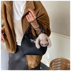 Detail of black leather bucket bag with silver clasp and cute plush rabbit pendant