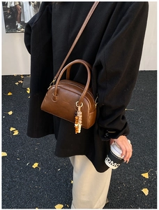 Brown retro bowling bag styled with beaded charm on side for winter fashion