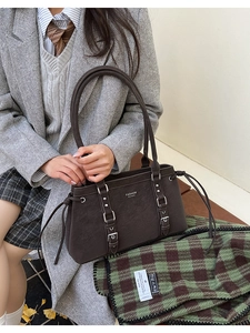 Dettaglio di borsa vintage in pelle martellata marrone con fibbie e rivetti argentati
