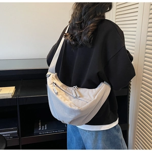 Detail of minimalist cream-white crescent crossbody bag with adjustable strap and smooth zipper