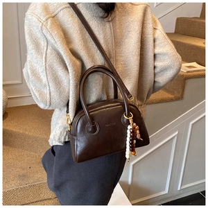 Detail of dark brown retro bowling bag with wood bead charm on indoor stairs
