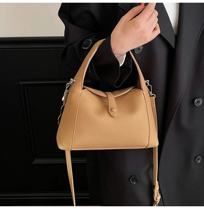 Detail of khaki pebbled leather bag featuring a folding design and adjustable strap