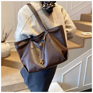 Detail of dark brown tote bag with retro leather texture and elegant tassel charm