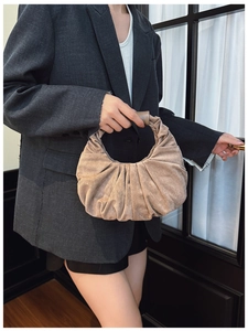 Detail of light brown suede handbag featuring pleated design and cylindrical handle