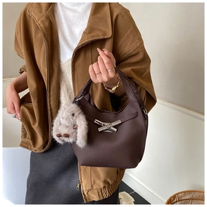 Detail of coffee brown bucket bag featuring silver bow buckle and plush rabbit charm