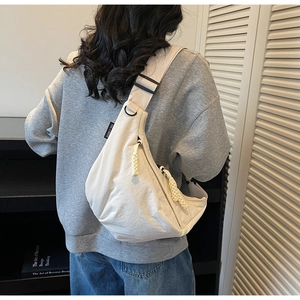 Detail of off-white hobo bag showing woven rope zipper and adjustable wide strap