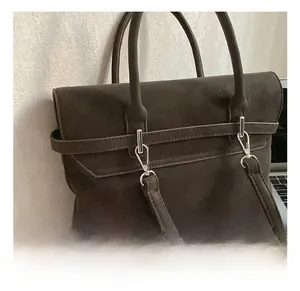 Detail of premium silver metal hooks and matte suede texture on the dark brown tote bag