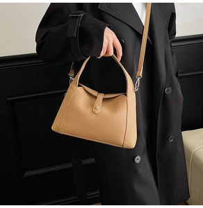 Close-up of camel leather texture and buckle detail on vintage minimalist shoulder bag