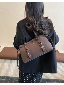 Dettaglio della borsa tote retrò marrone scuro con logo bianco e fibbie in metallo