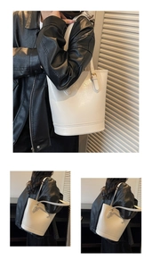 Close-up of a glossy white tote bag with adjustable shoulder strap and metallic buckles