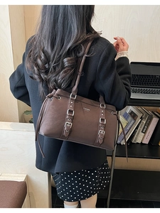 Dettaglio di una borsa hobo vintage marrone scuro con fibbie e lacci in un contesto lifestyle
