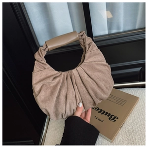 Close-up of brown suede hobo bag featuring pleated texture and leather handle details