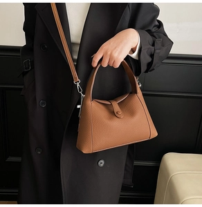 Detail of brown litchi pattern leather bag with side folds and silver metal hardware