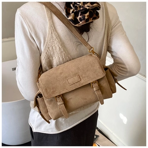 Detail of khaki suede shoulder bag featuring functional flap pockets and metal buckles
