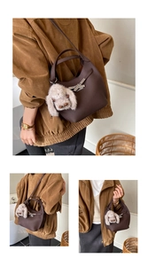 Detail of dark brown leather hobo bag featuring silver buckle and plush puppy charm
