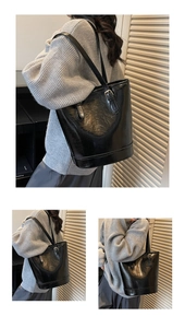 Detail of glossy black wax leather tote bag with metallic buckle and slim strap