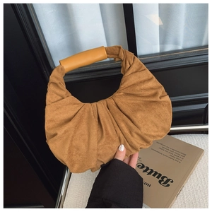Detail of caramel brown suede pleated handbag with smooth leather wrapped handle