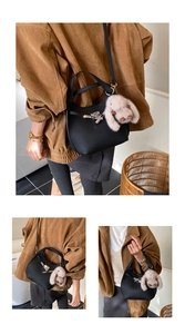 Detail of black saddle bag featuring silver clasp and plush white rabbit charm