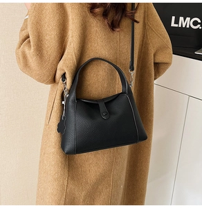 Close-up of black lychee grain leather handbag with silver hardware and shoulder strap