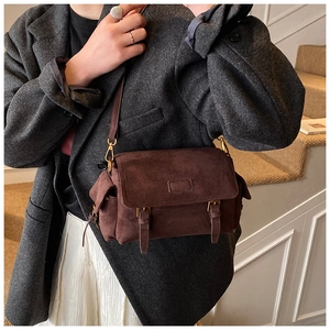 Detail of dark brown faux suede crossbody bag with vintage buckle and organza pleats